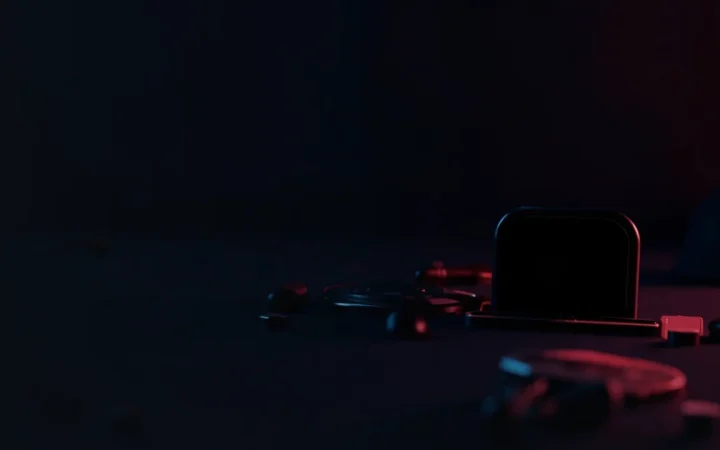 A dark desk with a hardware wallet, steel plate, padlock and shield lit in red.