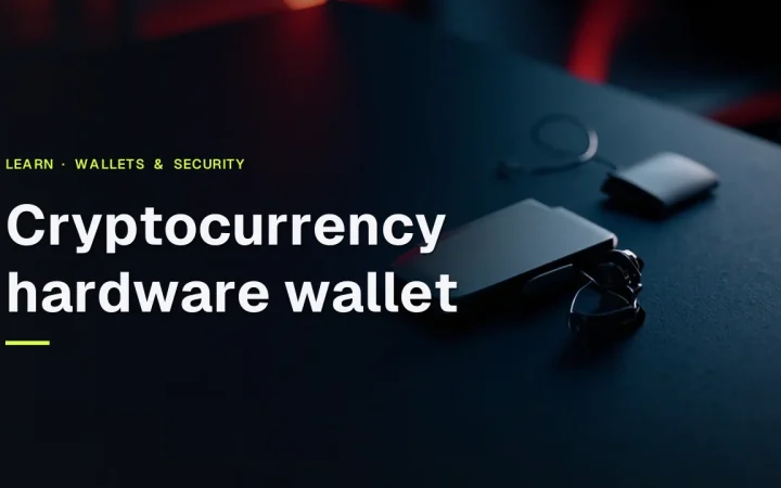 A hardware wallet with a blank screen and a steel plate on a dark desk, lit by red accents