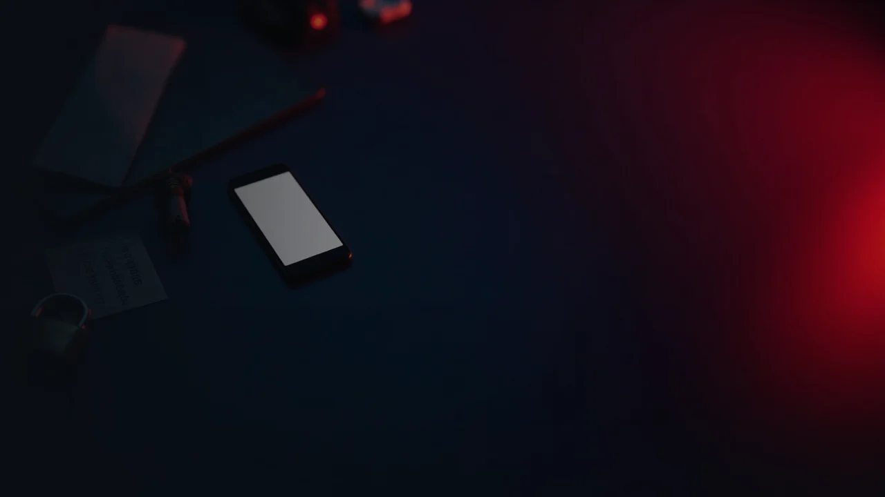 Et mørkt skrivebord med en telefon, bærbar computer, stålplade, hængelås og en papirlap oplyst af rød glød.