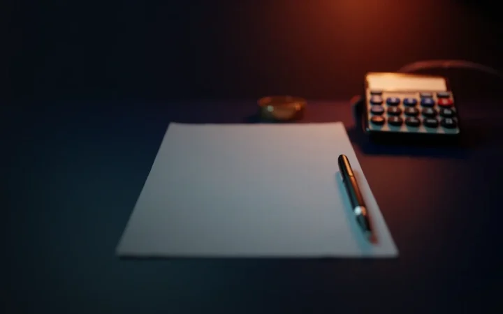 A dark navy background with a blank form, pen, and calculator on the right.