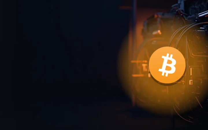 Bitcoin-logoet over rækker af glødende mining-maskiner og kabler.