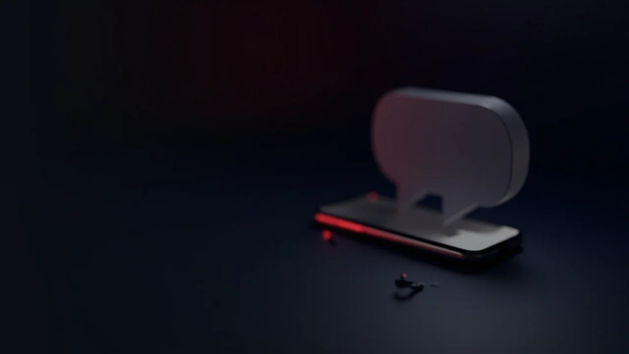 Une scène bleu marine sombre avec un téléphone vierge, une bulle de discussion et un porte-clés éclairés par une lueur rouge à droite, et une moitié gauche vide.
