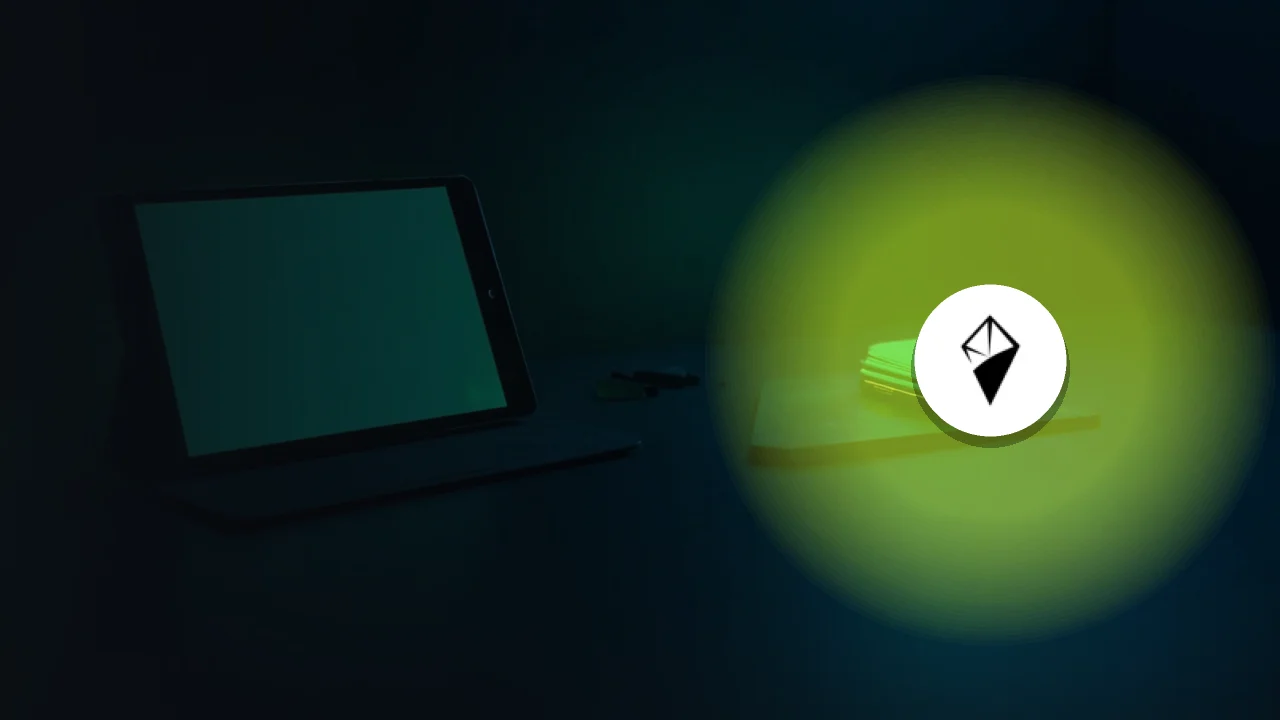 AINFT-logoet over et mørkt skrivebord med en tablet, en hardware-wallet og en stålplade i smaragdgrønt lys.