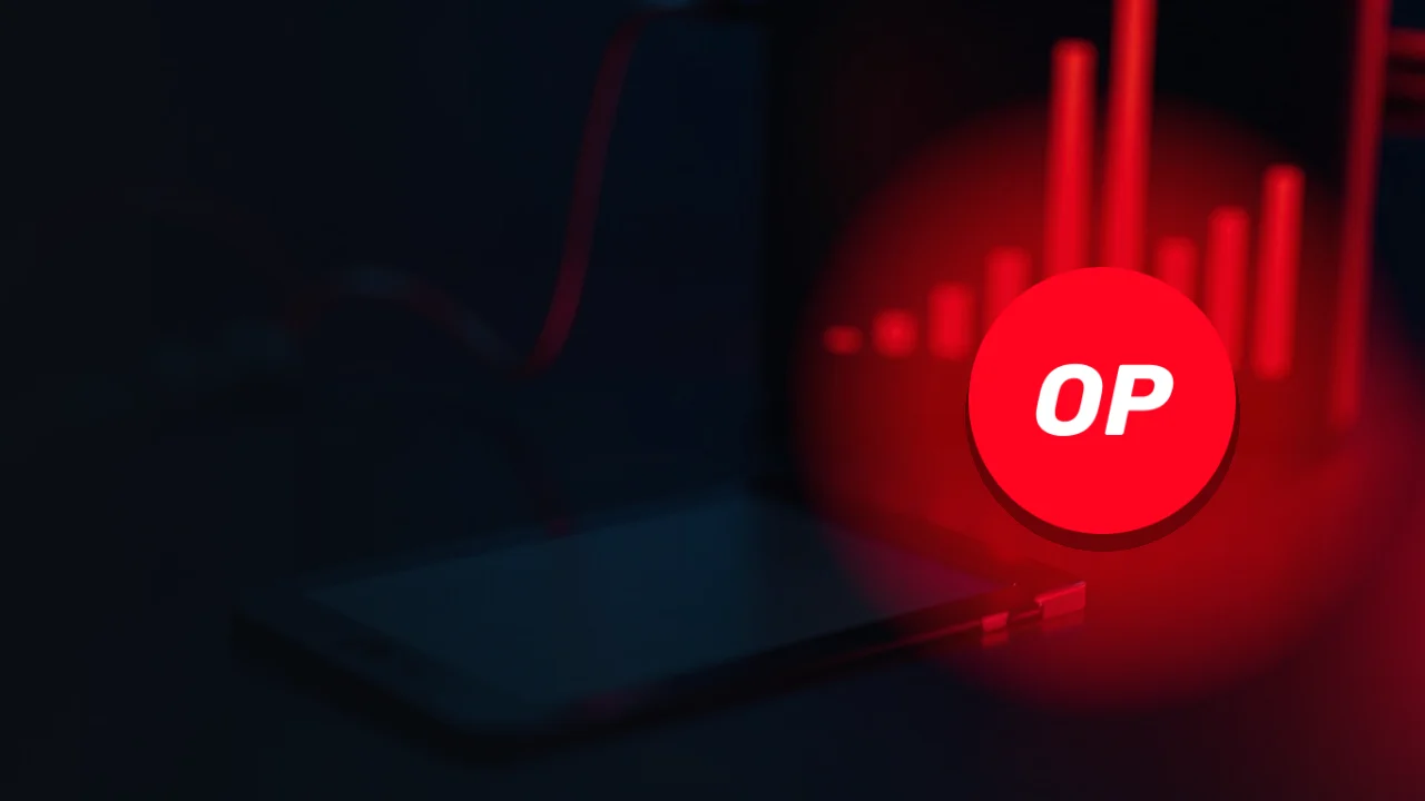 Das Optimism-Logo über einem dunklen Schreibtisch mit einem Wallet-Gerät, einem leuchtenden roten Kabel und einem Monitor mit roten Balken.