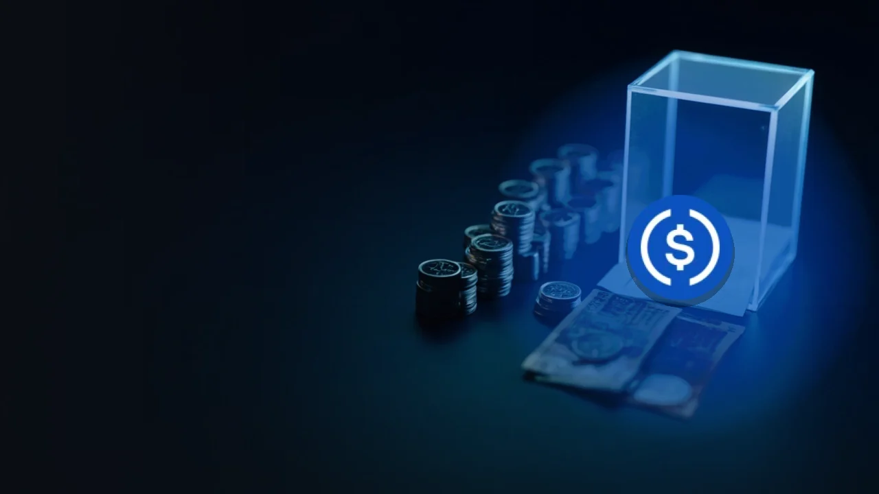 어두운 남색 배경의 빈 코인, 유리 금고, 빈 종이 위에 놓인 USD Coin 로고.