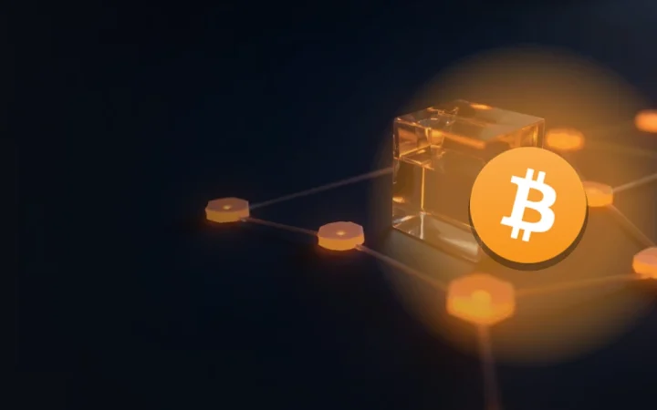 Bitcoin-logoet over en mørk navybaggrund med en glasterning forbundet med orange lys til mindre glasblokke til højre.