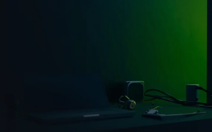 Un bureau bleu marine foncé avec un ordinateur portable vierge, un portefeuille matériel et un cadenas éclairés en vert lime.