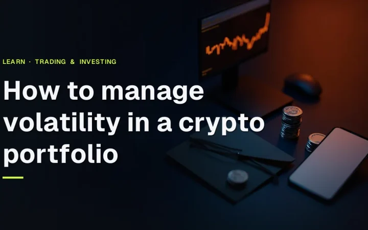 Der Titel Wie Sie die Volatilität in einem Krypto-Portfolio steuern über einem dunklen Schreibtisch mit leuchtenden orangefarbenen Charts, leeren Token und einem leeren Telefon.