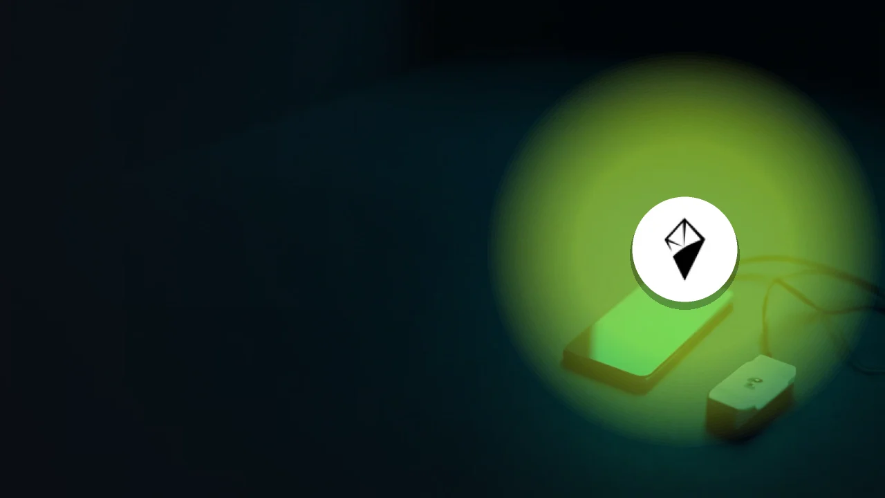 The AINFT logo over a dark desk with a phone, drive, and cable.