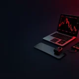 A dark desk with a laptop, phone and padlock glowing red.
