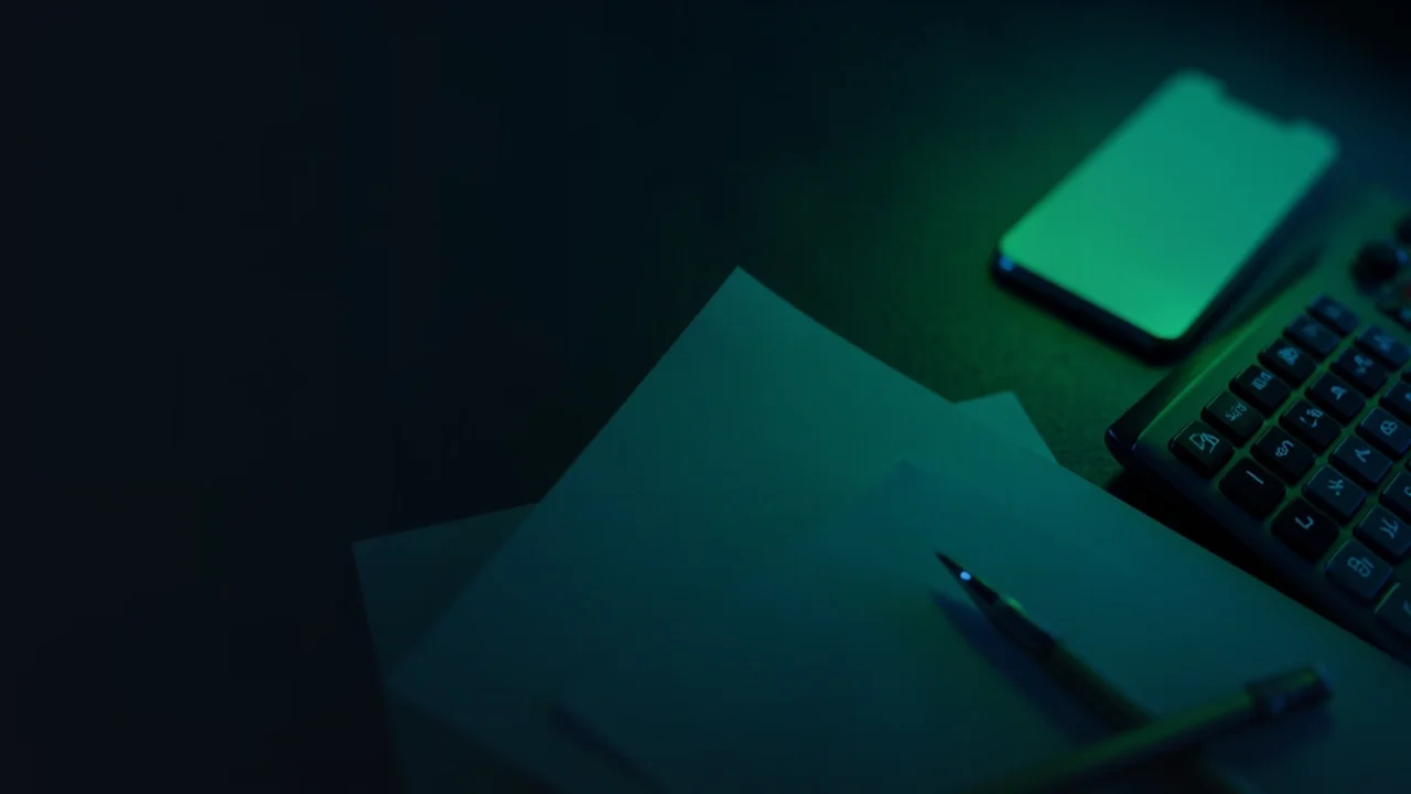Un escritorio oscuro con una calculadora y papeles.