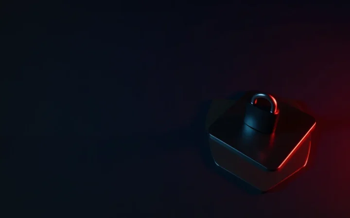 A dark desk with a hardware wallet, steel plate and padlock in red and navy.