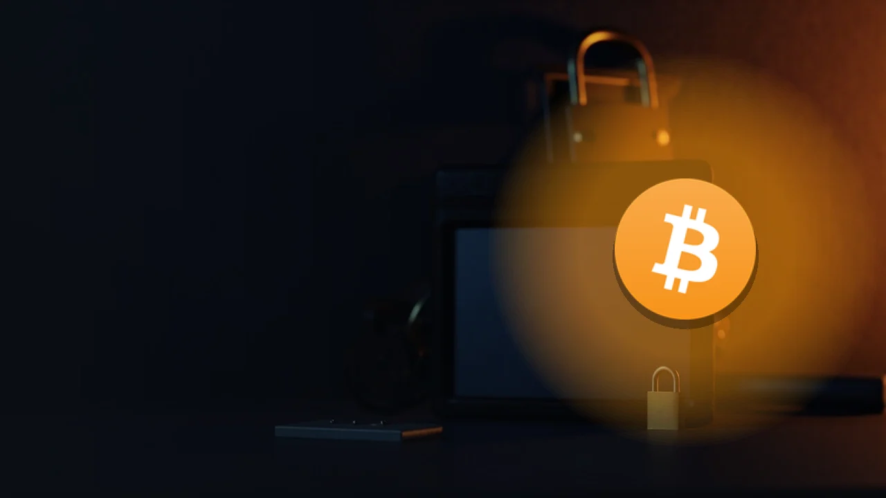 Bitcoin-logoet over et mørkt skrivebord med en hardware wallet, stålplade, hængelås og skjold oplyst i orange.