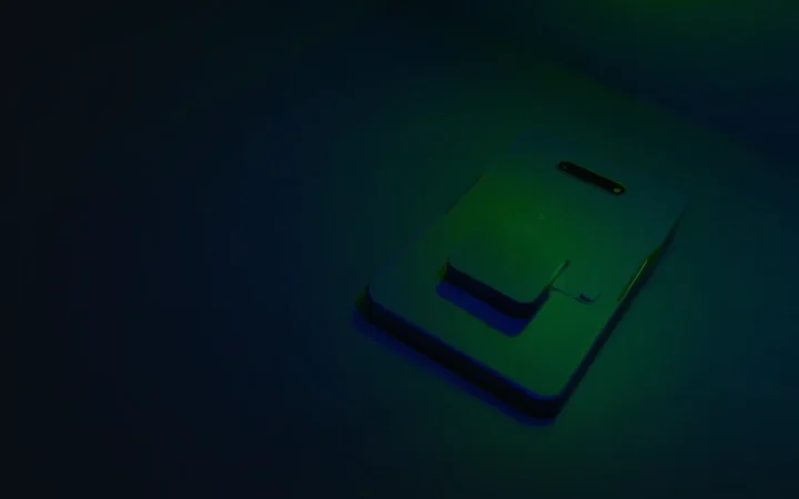 A blank phone, a matte debit card and a card reader on a dark navy desk lit with lime green.