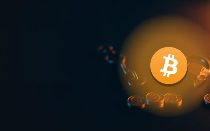 Bitcoin-logoet over en mørk navybaggrund med glødende orange mønter, en brudt kæde og en revnet hængelås.