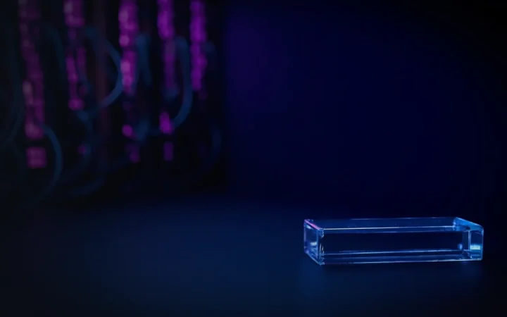 Rader av serverrack lyser violett, med ett glasblock på ett skrivbord; mörkblå bakgrund.