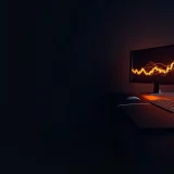 A dark navy desk with glowing orange monitors showing abstract charts.