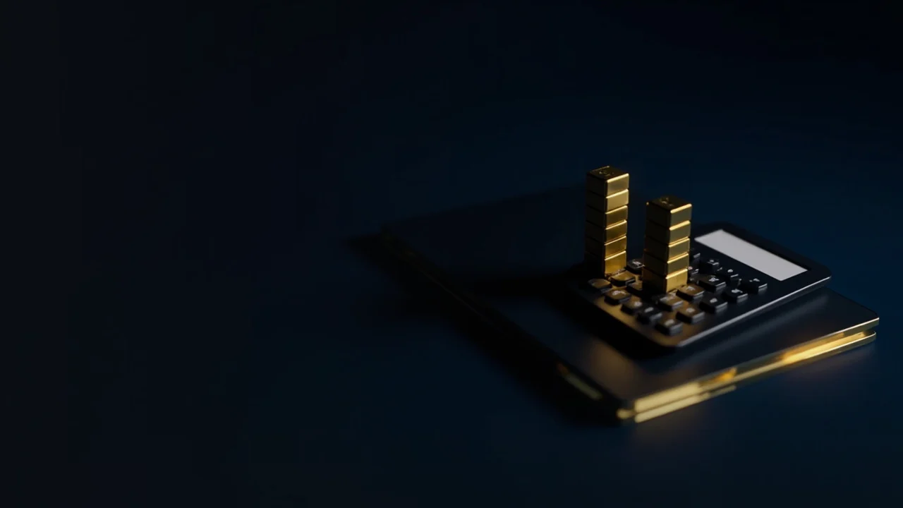 Un escritorio oscuro con barras doradas brillantes del libro de órdenes y una calculadora en blanco.