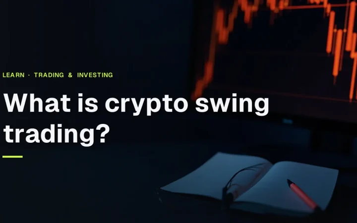 Titlen Hvad er crypto swing trading vises over et mørkt skrivebord med et glødende candlestick-diagram og en lukket notesbog.
