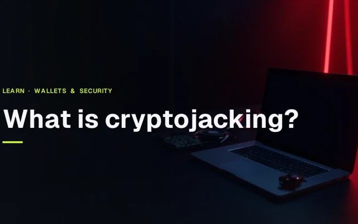 Titlen What is cryptojacking? over en mørk navybaggrund med en glødende rød laptop og et printkort til højre.