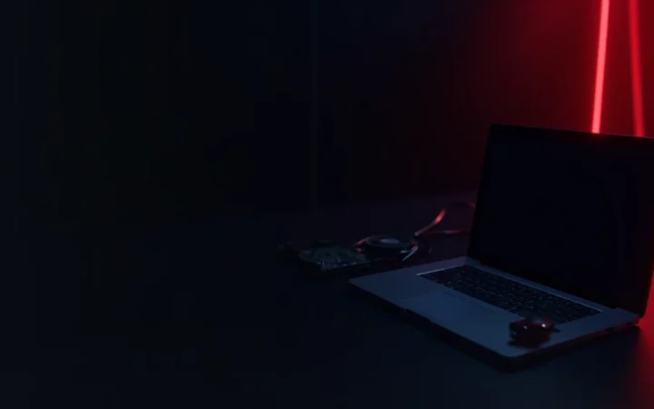 En mørk navyblå baggrund med en glødende rød laptop og et circuit board til højre.