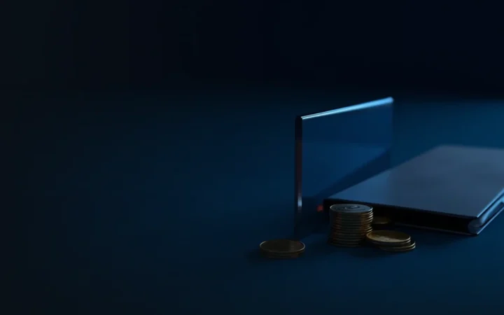 En mørk navybaggrund med en stak blanke metalmønter, et glaspanel og en mappe oplyst af blåt lys.