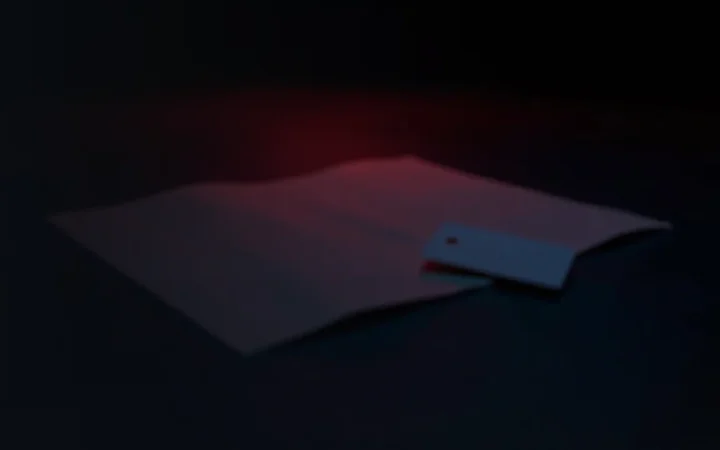 A dark desk with blank paper and a key card lit in red.