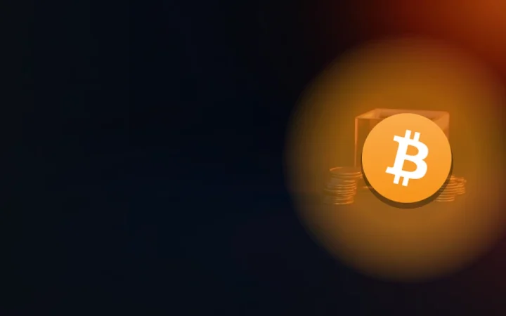 Bitcoin-logoet over en mørk navybaggrund med stakke af blanke mønter og en glasvault oplyst i orange.