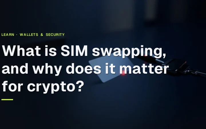 A blank phone chip card, a dark phone with a blank screen and a metal key on a navy desk, lit by a red glow.