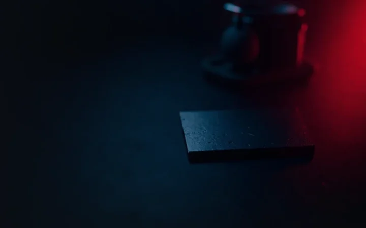 A dark desk with a hardware wallet with a blank screen and a steel plate.