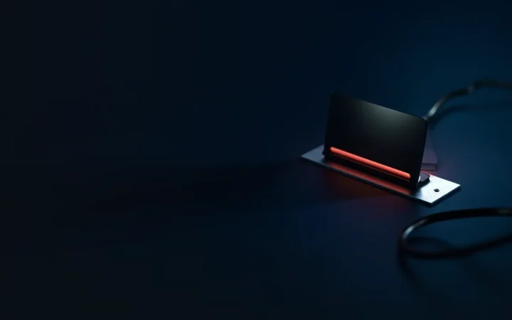 A hardware wallet with a blank screen and a steel plate on a dark navy desk.