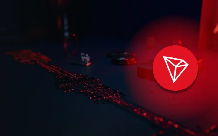 Le logo TRON sur un bureau bleu marine foncé avec des jetons métalliques vierges, un bloc de verre et un portefeuille matériel.