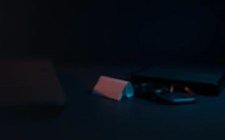 En mørk navy scene med en blank stålplade, en skærmløs hardware wallet, blankt papir og en hængelås i rødt lys.